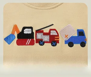 Close-up of colorful cartoon construction vehicle embroidery on beige cotton sweatshirt
