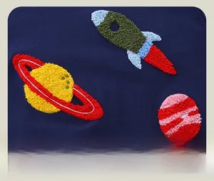 Detail of towel embroidered rocket and planet patches on navy cotton sweatshirt