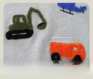 Detail of colorful towel embroidery featuring construction vehicles on grey cotton sweatshirt