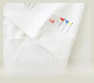 Detail des Rippsaums am weißen Baumwoll-Sweatshirt mit rot-blau-gelber Flaggen-Stickerei