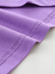 Detailed close-up of stitching and purple cotton knit fabric on a girls long sleeve tee