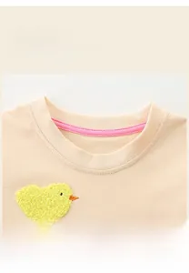 Detail of round neckline with reinforced pink tape and chick embroidery on cotton dress
