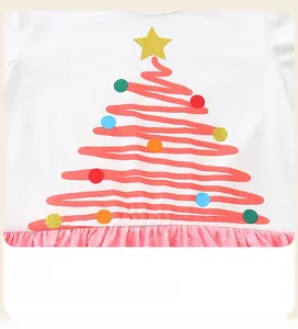 Close-up of cute Christmas tree print on white cotton dress with pink polka dot hem