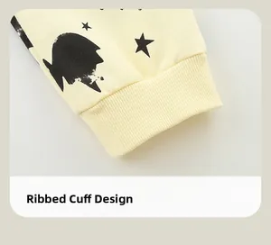Detail of light yellow kids pants featuring black star prints and ribbed cuff design