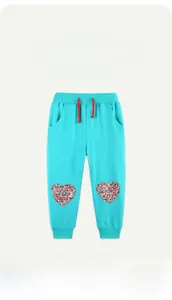 Detail of teal cotton sweatpants showing heart floral patches and red drawstring cord