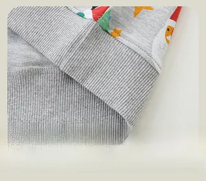 Dettaglio della felpa grigia da bambino con bordo a coste e stampe natalizie festive
