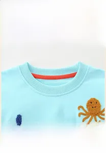 Detail of ribbed crew neck on light blue cotton girls sweatshirt with octopus towel embroidery