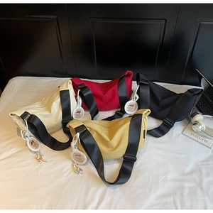 Detailed view of four colorful half-moon nylon crossbody bags with trendy charms