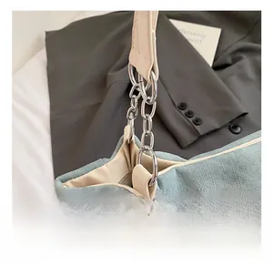 Close-up of silver metal hardware rings connecting light blue fabric and beige leather