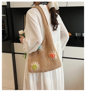Détail du sac cabas en maille avec fleurs 3D porté par un mannequin en robe blanche