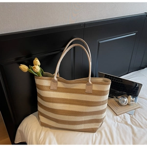 Détail d'un sac cabas tissé à rayures avec lanières en cuir et esthétique chaleureuse