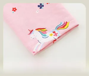 Detail of pink cotton leggings hem featuring colorful cartoon unicorn and floral prints