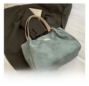 Detail of blue corduroy tote bag with cream leather handles and silver metal hardware