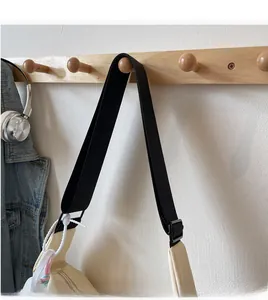 Close-up of adjustable wide black shoulder strap on minimalist cream crossbody bag