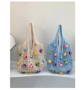 Detail of crochet tote bags with colorful handmade flowers on a white display stand