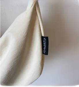 Close-up of the cream canvas dumpling bag showing the black BAVATU woven side label