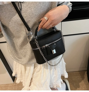 Detail view of black lychee grain leather handbag with silver chain and metal lock decoration