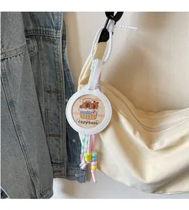 Detail of creative Capybara charm with colorful beads and cords on a canvas bag