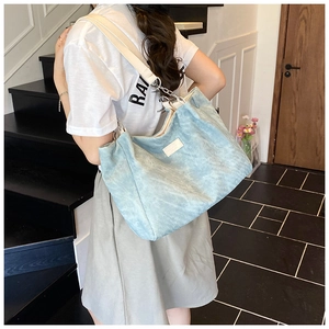 Detail view of light blue corduroy tote bag with white strap and silver chain accents