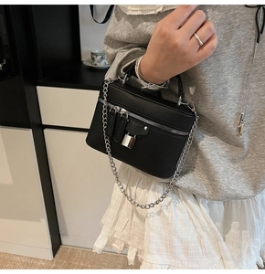 Detail of black pebbled leather box bag with silver padlock and chain strap