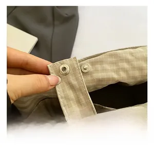 Detail of silver snap button closure on khaki plaid fabric crossbody bag for women