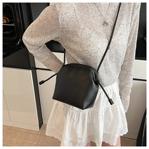 Détail du sac à bandoulière en cuir noir grainé avec fermeture à cordon sur le modèle