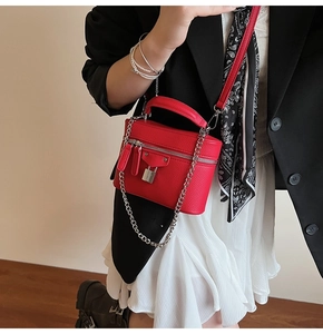 Detail of red leather crossbody bag with lychee grain texture and silver chain strap