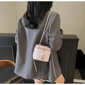 Dettaglio mini borsa a secchiello trapuntata rosa con rivetti e ciondolo a camelia