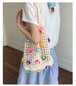 Detail of handmade crochet tote bag with 3D floral accents and woven mesh texture