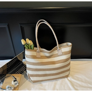 Détail d'un sac cabas tissé à rayures avec ordinateur et accessoires dans une scène de vie