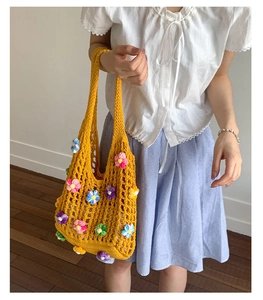 Close-up of yellow crochet tote bag with colorful 3D floral accents and woven handle