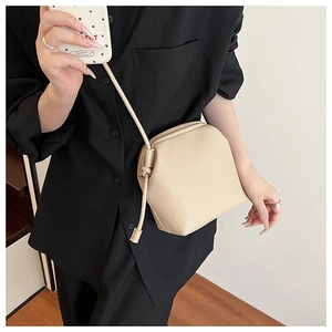 Detail of apricot crossbody bag with knot shoulder strap and lychee grain leather texture