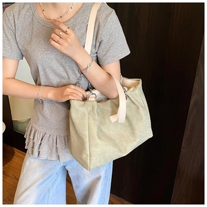 Detail of sage green tote bag with wide straps and silver rings on model