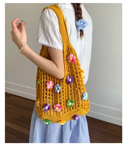 Close-up of yellow crochet shoulder bag featuring colorful 3D knitted flower details