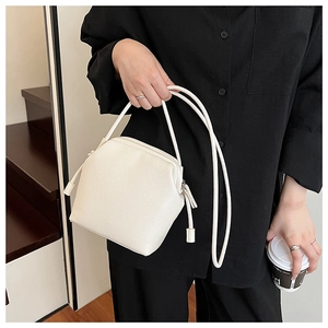 Detail of cream-white lychee pattern leather crossbody bag with tassel zipper and strap