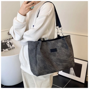 Detail of grey tote bag showing logo patch and metal chain link with leather strap