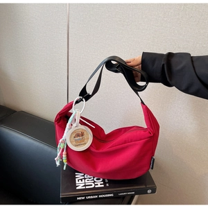 Detail of rose red nylon crescent bag with adjustable strap and capybara charm