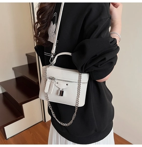 Detail of white pebbled leather crossbody bag with silver chains and long tassels