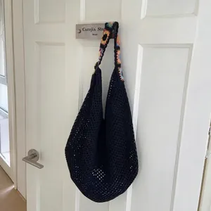 Détail du sac cabas en crochet noir avec bandoulière tricotée à motifs tournesols
