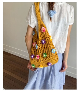 Close-up of handmade yellow crochet beach bag with colorful 3D floral knit decorations