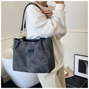 Detail of dark grey suede tote bag with black strap and Fashion Bag logo label