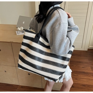 Detail of striped woven tote bag with durable black straps and high-capacity texture