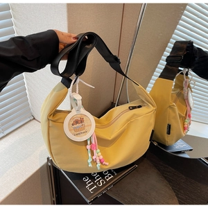 Detail of yellow nylon hobo bag with black adjustable strap and cute capybara pendant