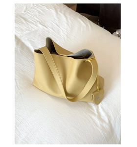 Dettaglio della borsa tote in pelle giallo zenzero con ciondolo a cuore e tracolla larga