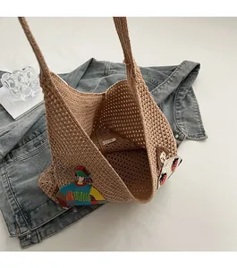Close-up of brown crochet knit tote bag featuring strawberry and portrait embroidery