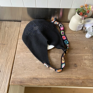 Détail de la bandoulière au crochet avec motifs floraux colorés sur un sac fourre-tout noir