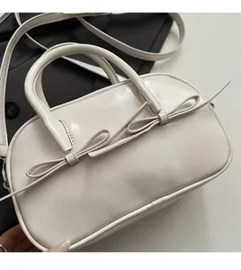 Détail d'un sac à main en similicuir crème avec nœuds décoratifs et double fermeture