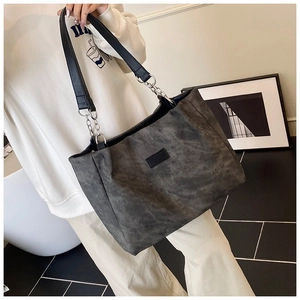 Detail of dark grey tote bag with black leather straps and metal chain link accents