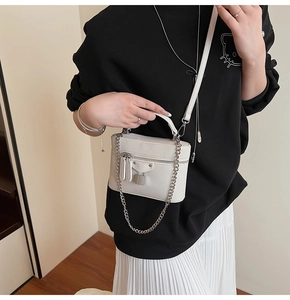 Detail of white box bag with litchi grain leather, silver lock, and stud embellishments