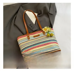 Detail of colorful striped straw beach bag with brown leather handles and sunflower charm